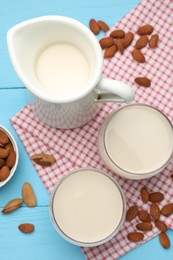 Photo of Fresh nut milk and almonds on light blue wooden table, flat lay