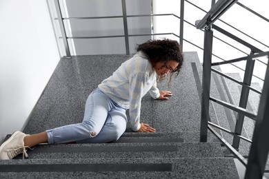 Injured woman on stairs in building after fall. Dangerous accident