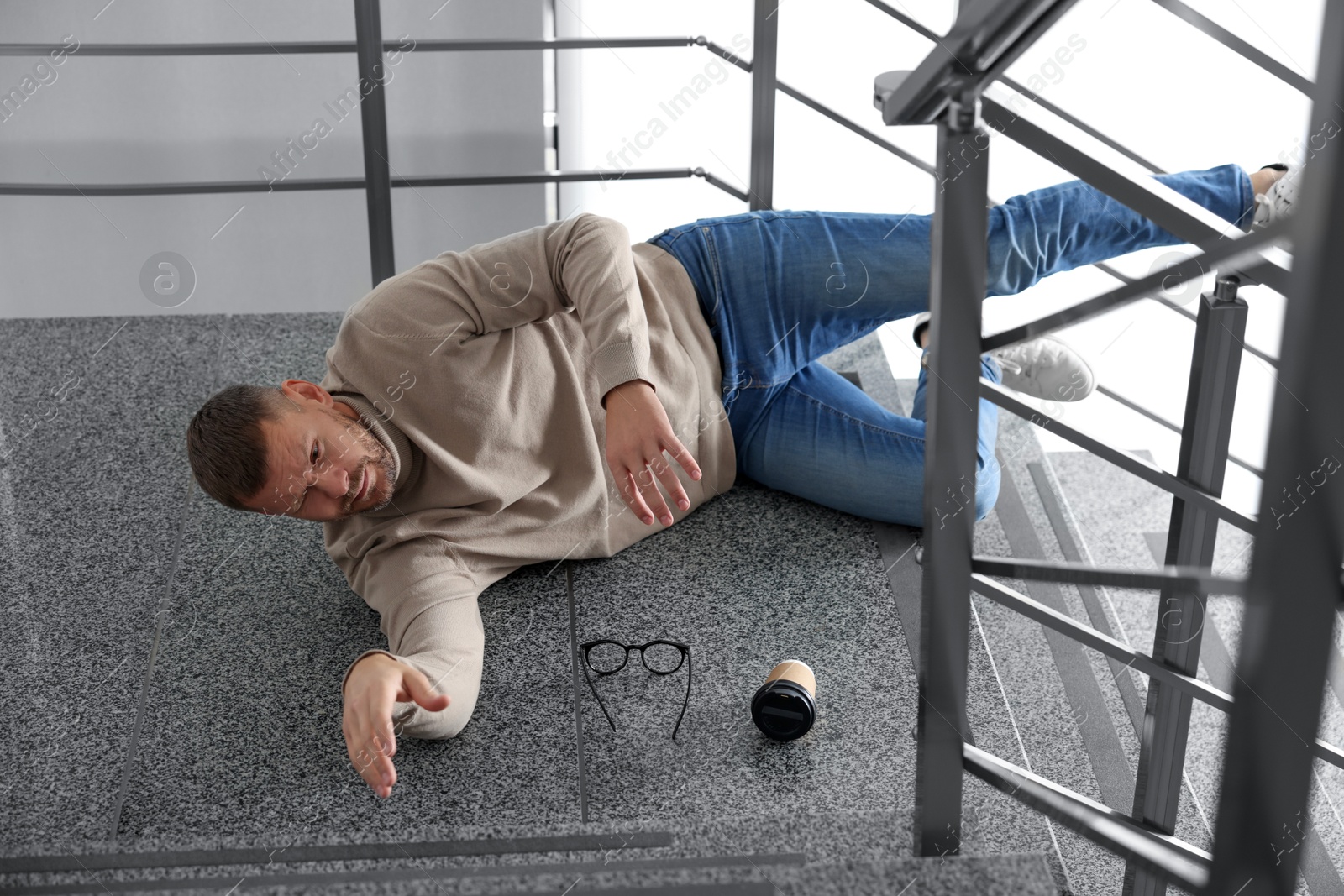 Photo of Injured man on stairs in building after fall. Dangerous accident