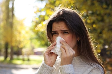 Young woman with runny nose in park