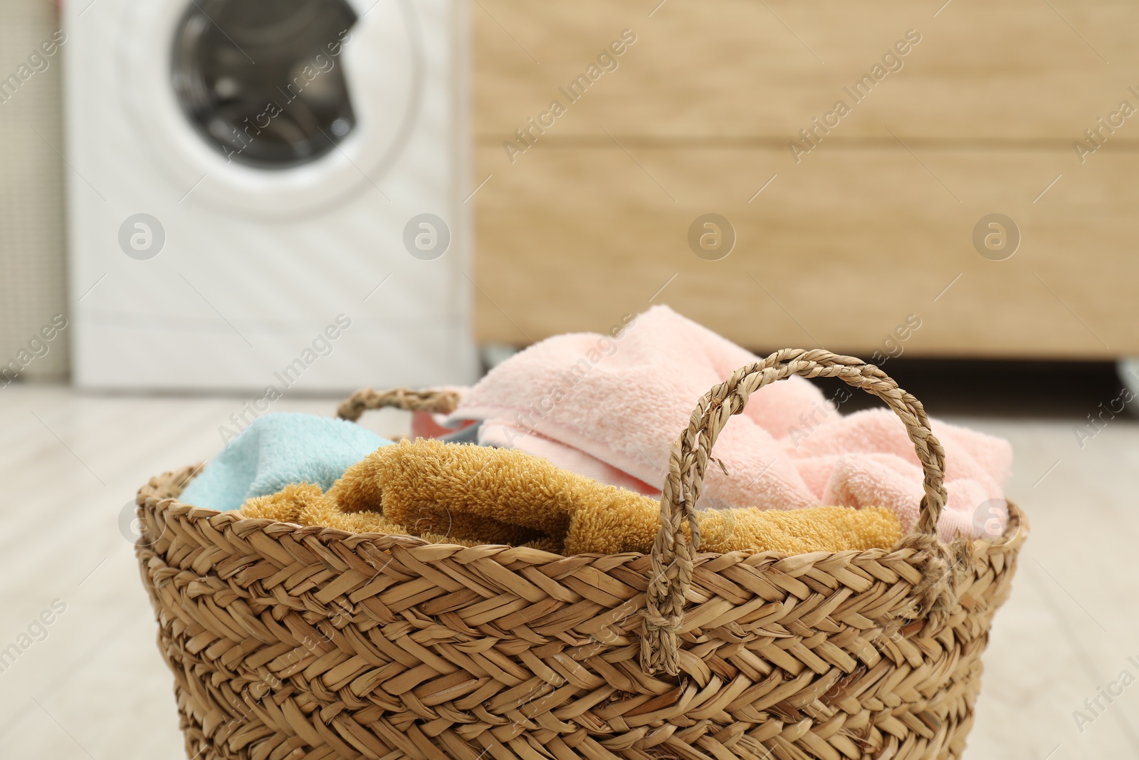 Photo of Wicker basket full of laundry in bathroom, closeup