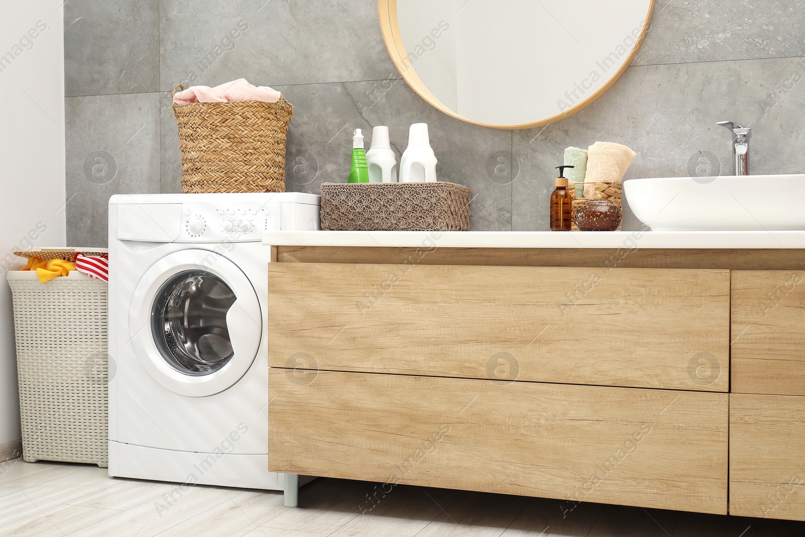 Photo of Wicker baskets full of laundry, washing machine and detergents in bathroom