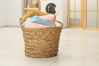 Photo of Wicker basket full of laundry in bathroom