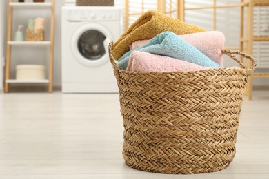 Photo of Wicker basket full of laundry in bathroom