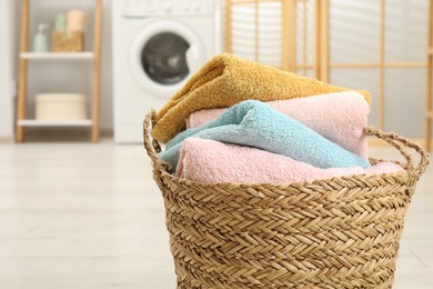 Photo of Wicker basket full of laundry in bathroom, closeup. Space for text