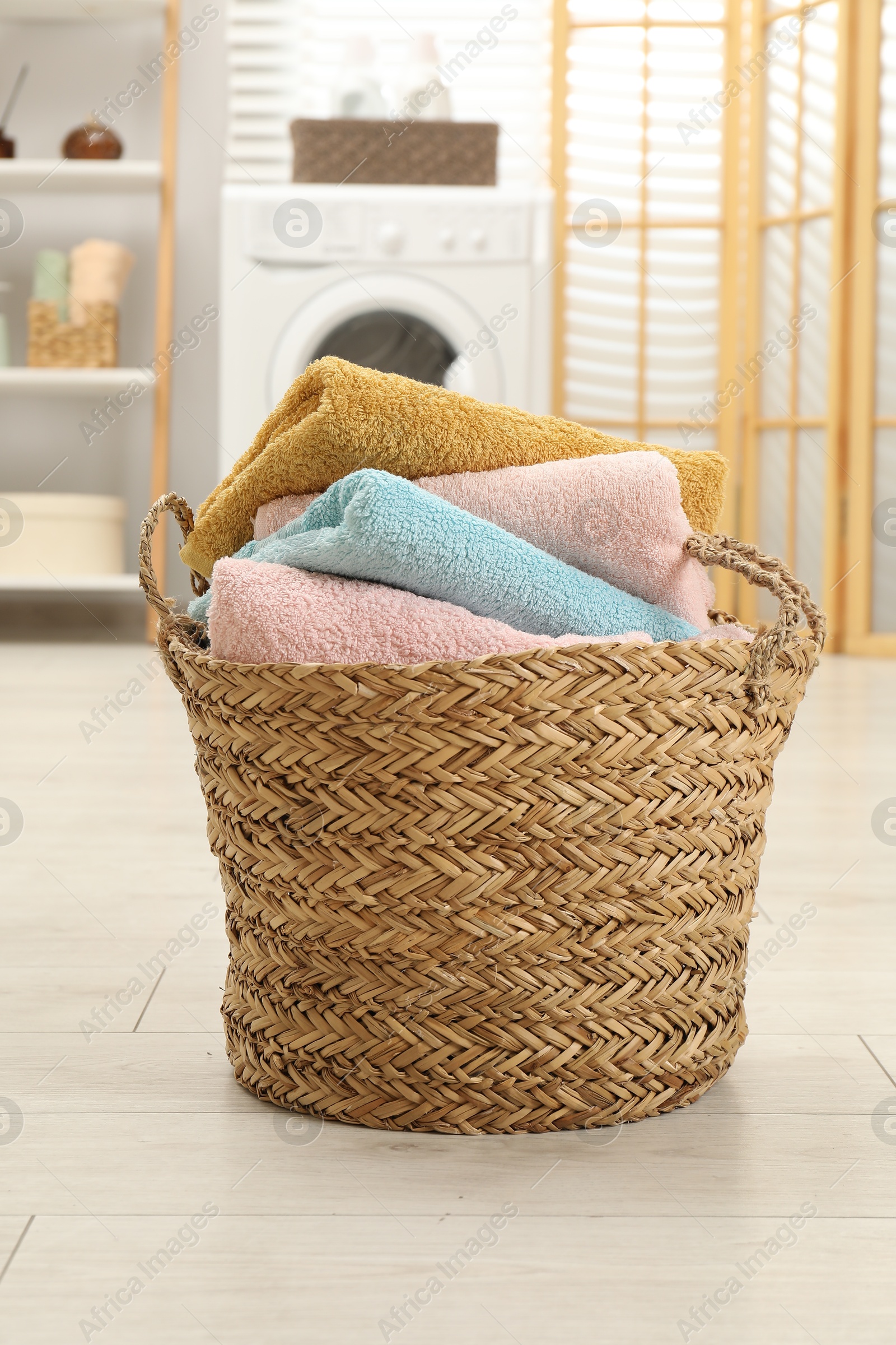 Photo of Wicker basket full of laundry in bathroom