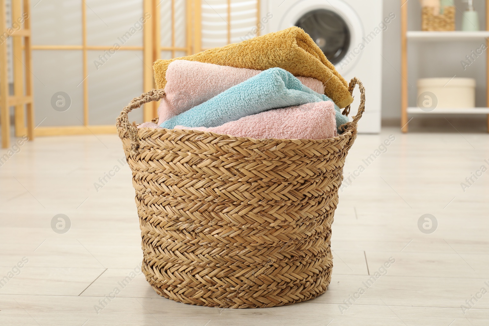 Photo of Wicker basket full of laundry in bathroom