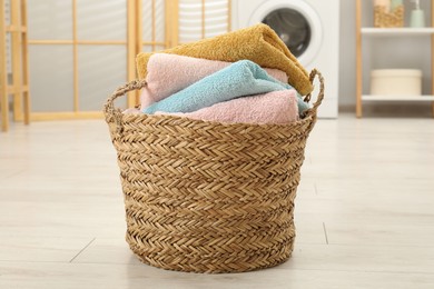 Photo of Wicker basket full of laundry in bathroom