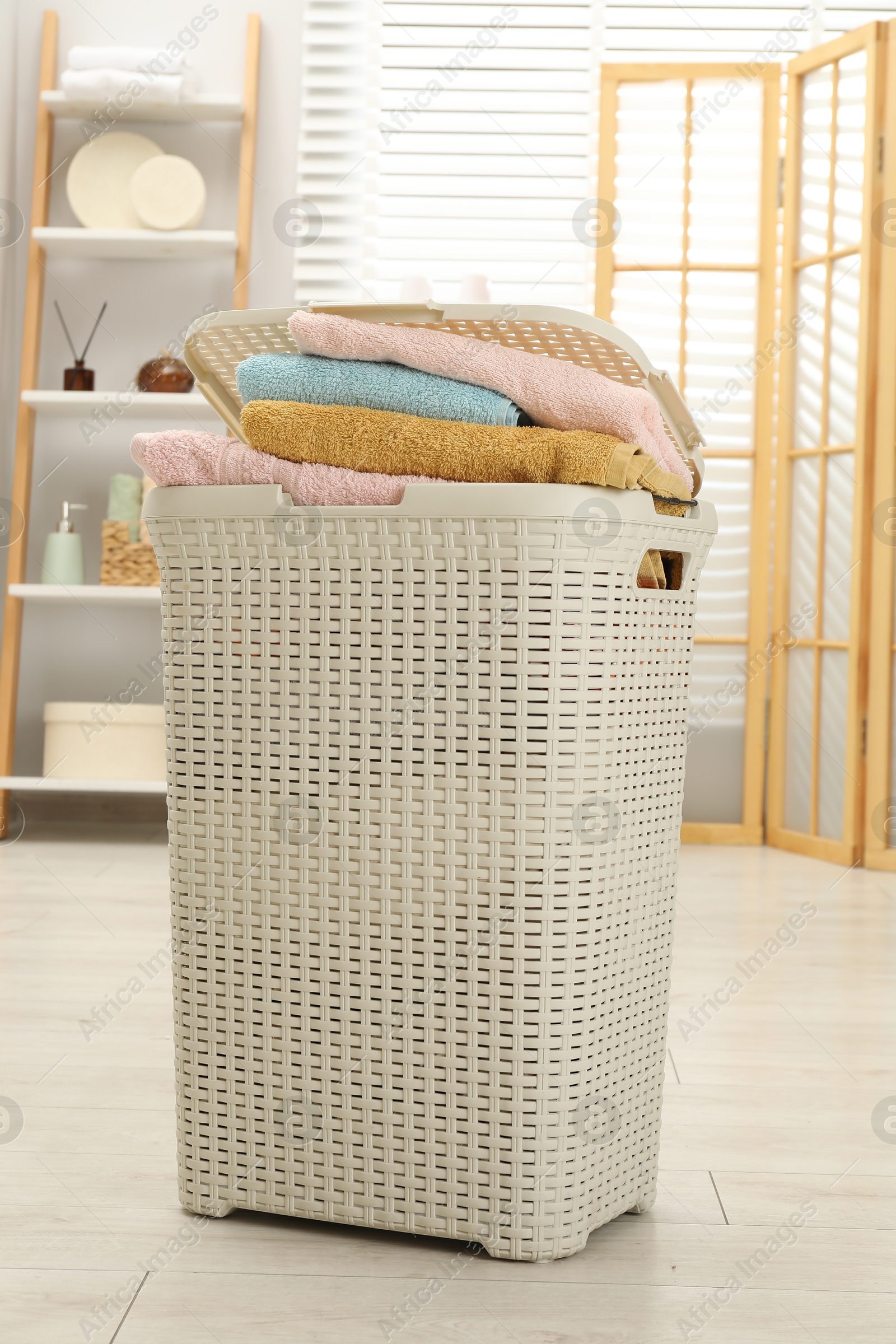 Photo of Wicker basket full of laundry in bathroom