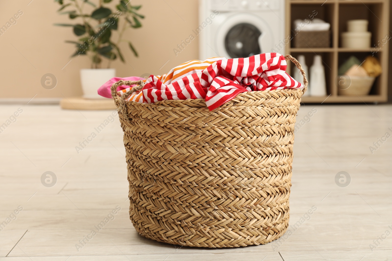 Photo of Wicker basket full of laundry in bathroom