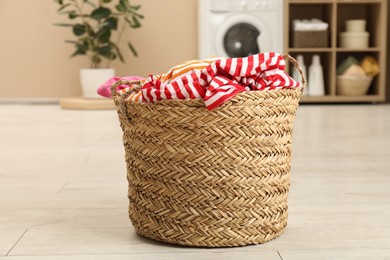 Photo of Wicker basket full of laundry in bathroom