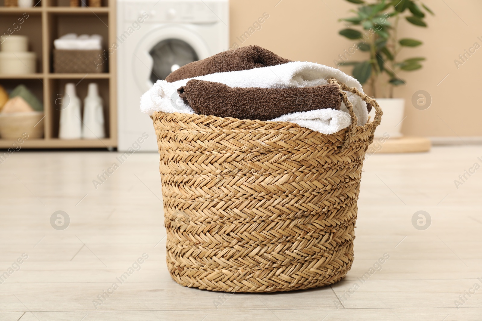 Photo of Wicker basket full of laundry in bathroom