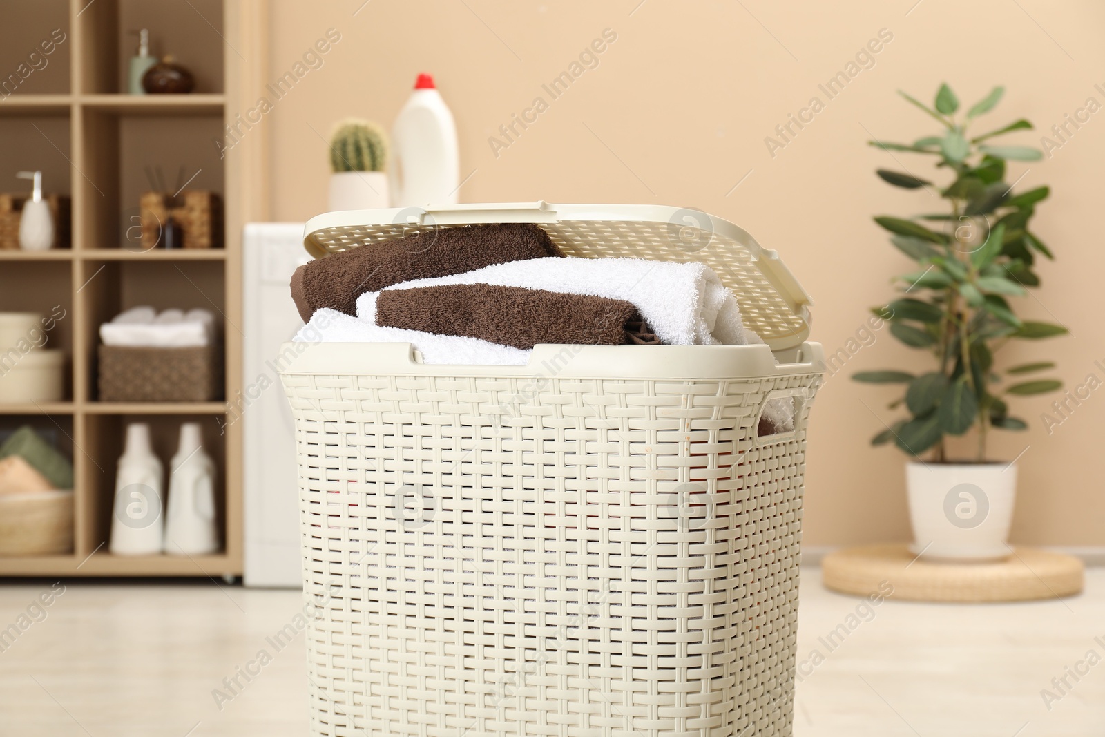 Photo of Wicker basket full of laundry in bathroom