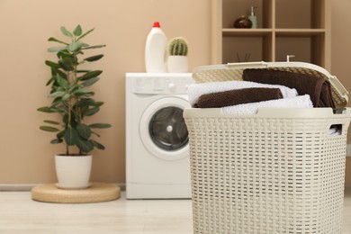 Photo of Wicker basket full of laundry in bathroom