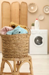 Photo of Wicker basket full of laundry on chair in bathroom