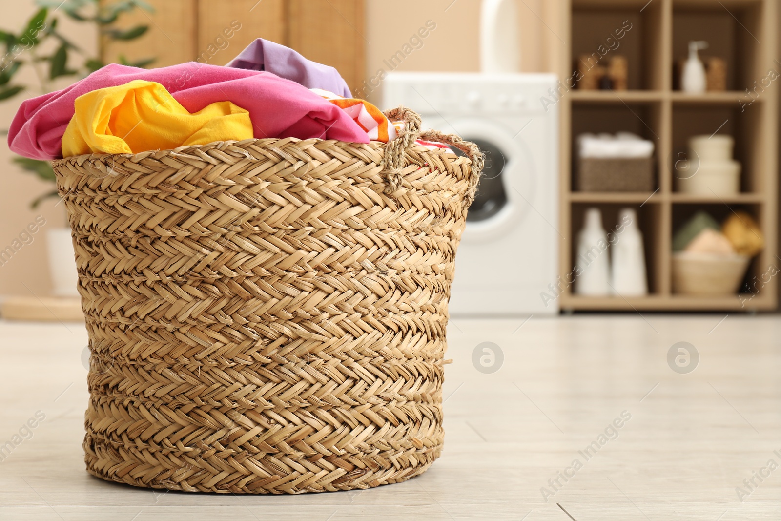 Photo of Wicker basket full of laundry in bathroom