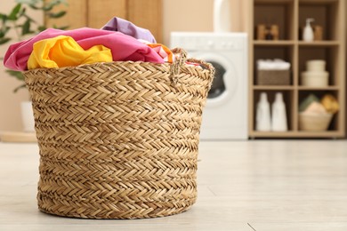 Photo of Wicker basket full of laundry in bathroom