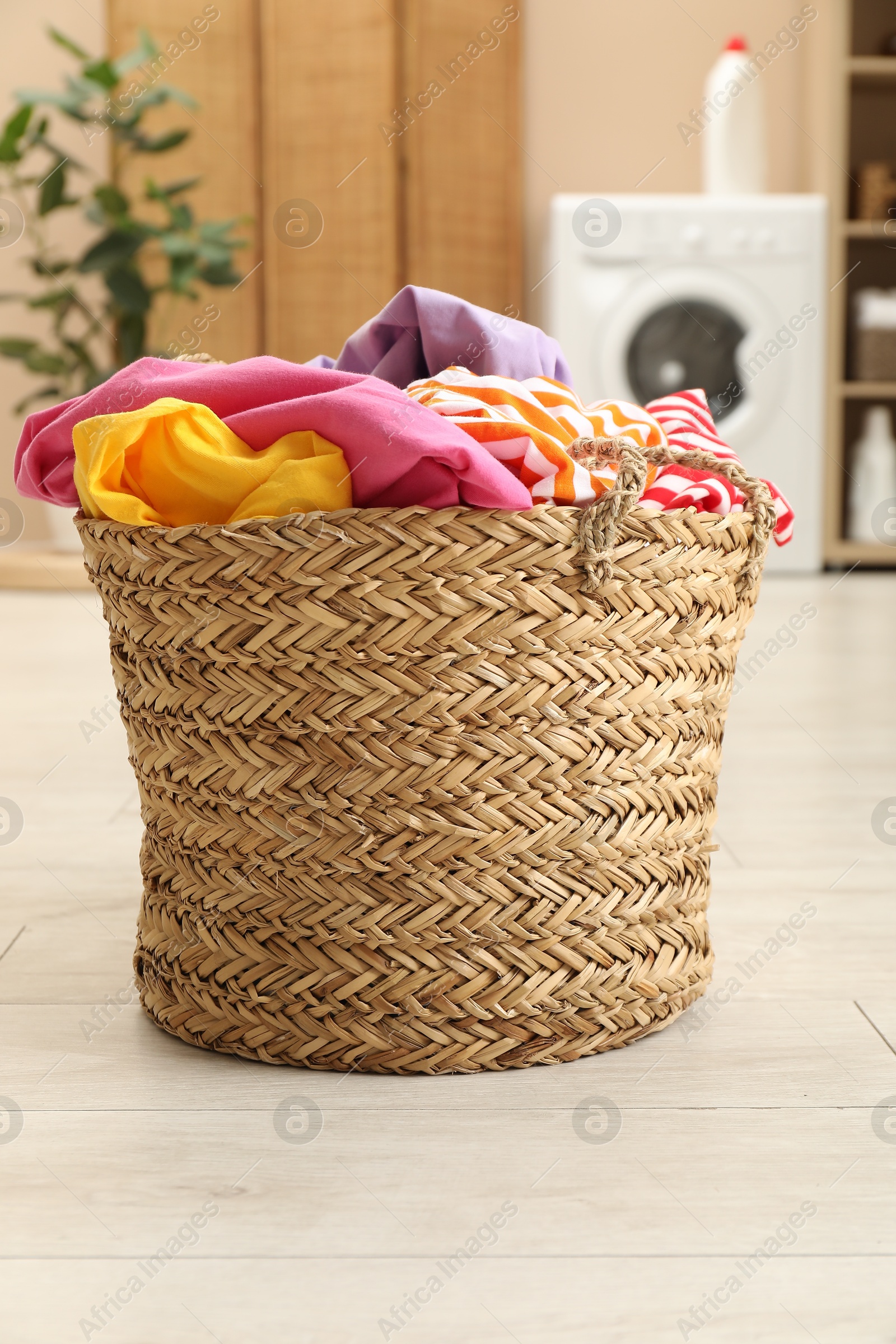 Photo of Wicker basket full of laundry in bathroom