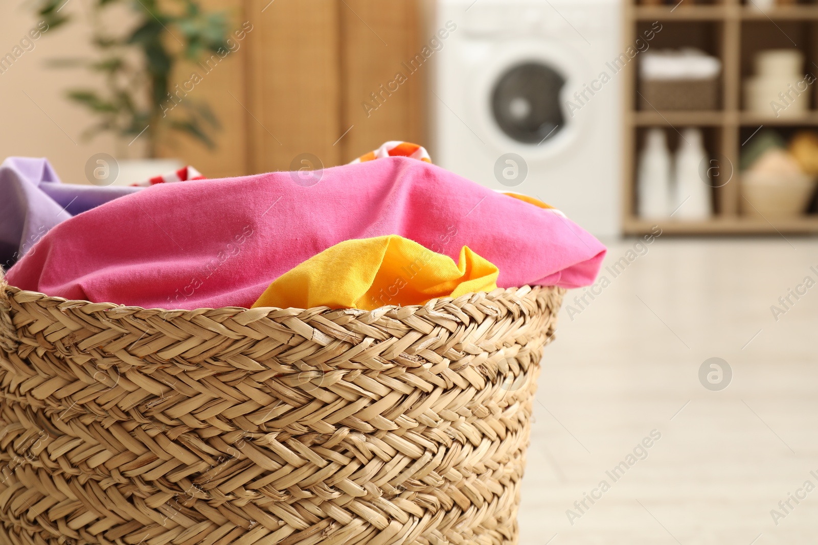 Photo of Wicker basket full of laundry in bathroom, closeup. Space for text