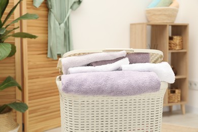 Photo of Wicker basket full of laundry in bathroom, closeup