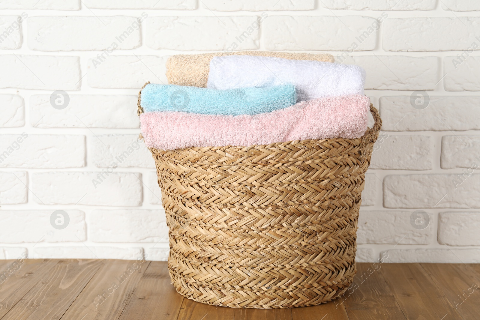 Photo of Wicker basket full of laundry on wooden table