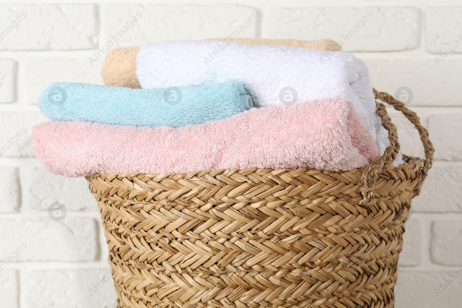 Photo of Wicker basket full of laundry against white brick wall, closeup