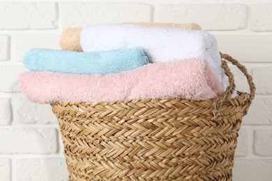 Photo of Wicker basket full of laundry against white brick wall, closeup