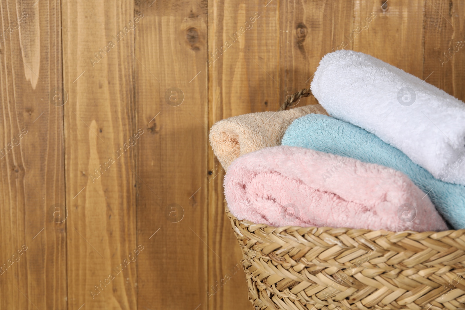 Photo of Wicker basket full of laundry against wooden background, closeup. Space for text