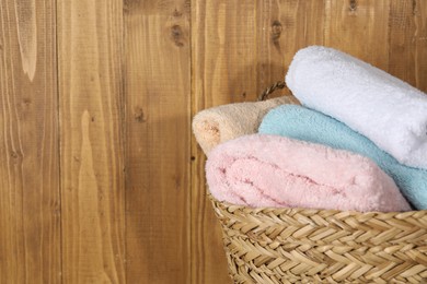 Photo of Wicker basket full of laundry against wooden background, closeup. Space for text