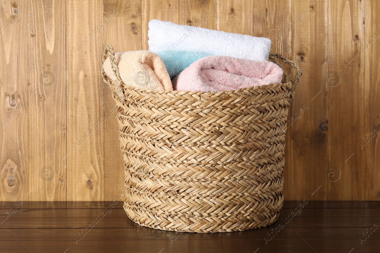 Photo of Wicker basket full of laundry on wooden table