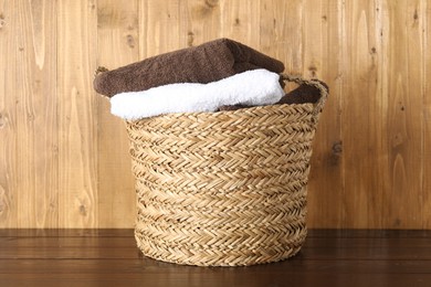 Photo of Wicker basket full of laundry on wooden table