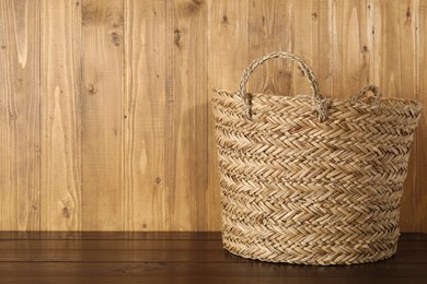 Photo of One wicker laundry basket on wooden table, space for text