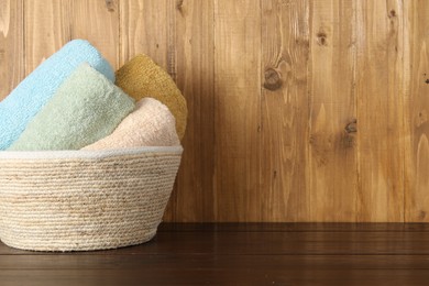 Photo of Wicker basket full of laundry on wooden table, space for text