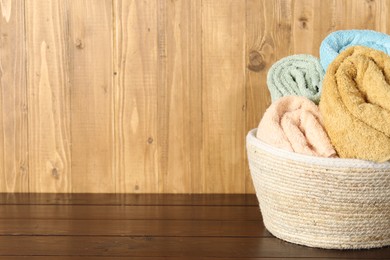 Photo of Wicker basket full of laundry on wooden table, space for text