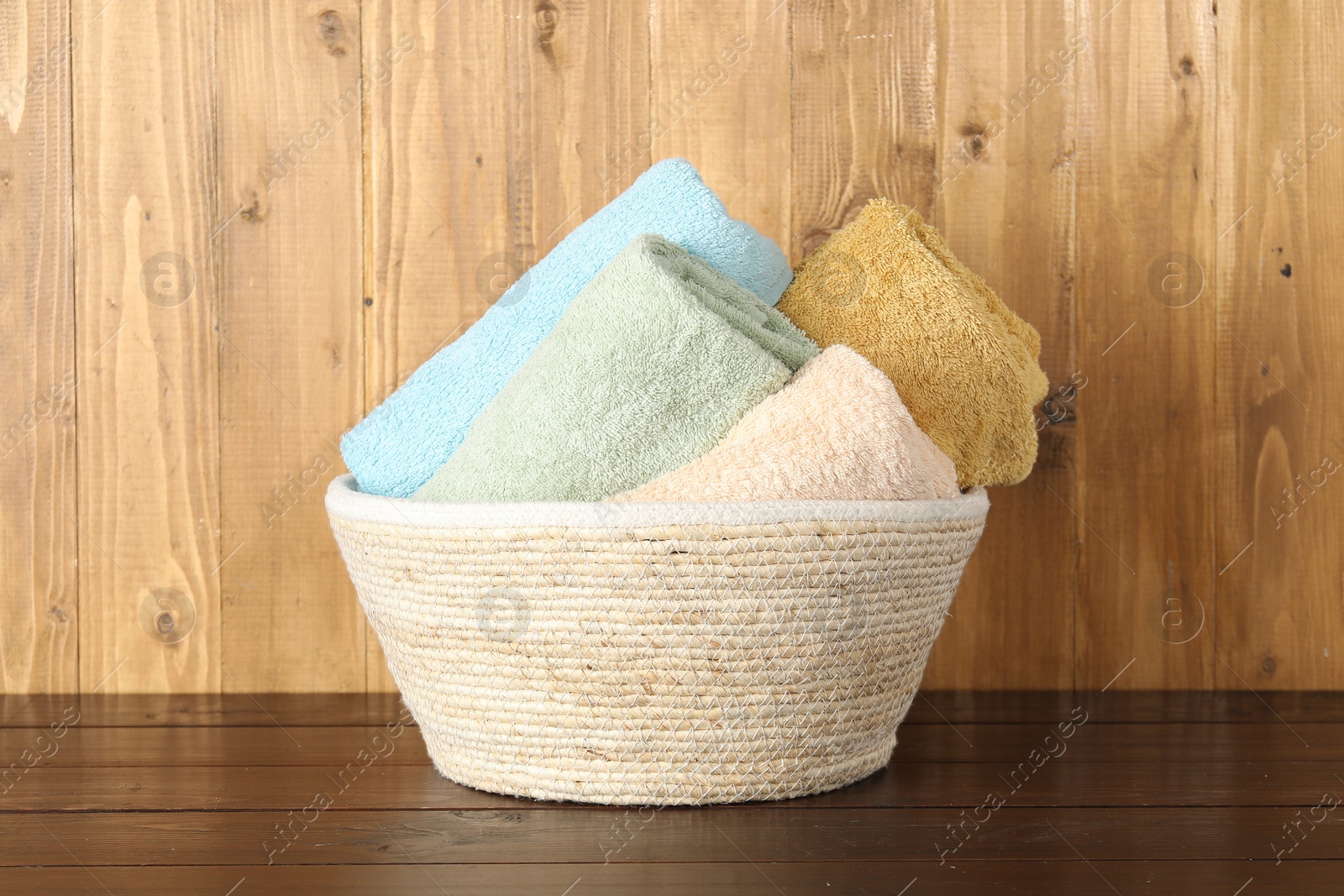 Photo of Wicker basket full of laundry on wooden table