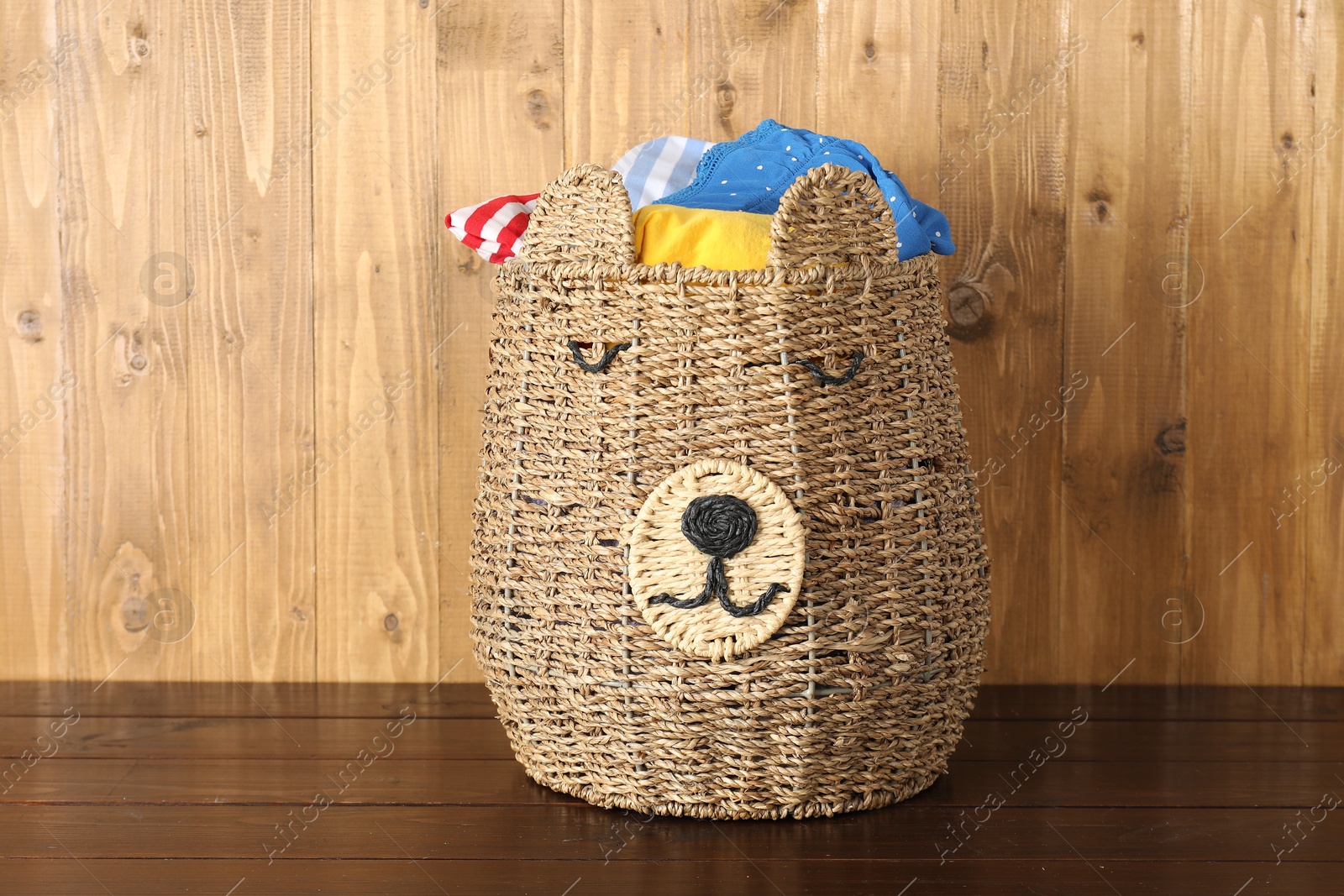 Photo of Wicker basket full of laundry on wooden table