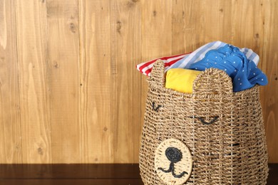 Photo of Wicker basket full of laundry on wooden table, space for text