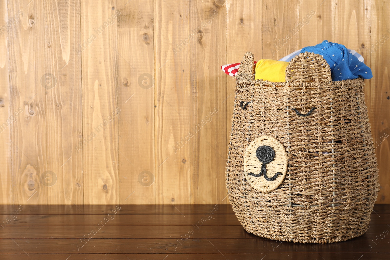 Photo of Wicker basket full of laundry on wooden table, space for text