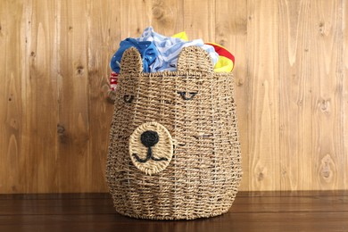 Photo of Wicker basket full of laundry on wooden table