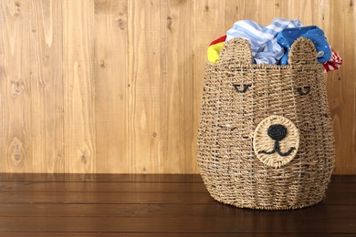 Photo of Wicker basket full of laundry on wooden table, space for text