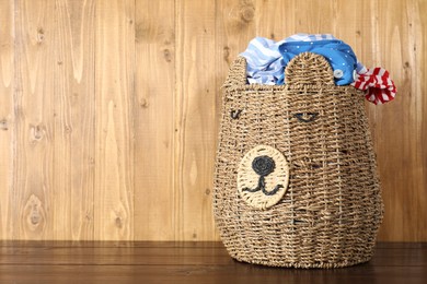 Photo of Wicker basket full of laundry on wooden table, space for text