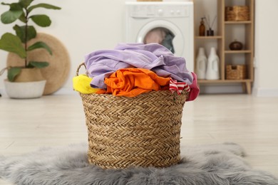 Photo of Wicker basket full of laundry in bathroom