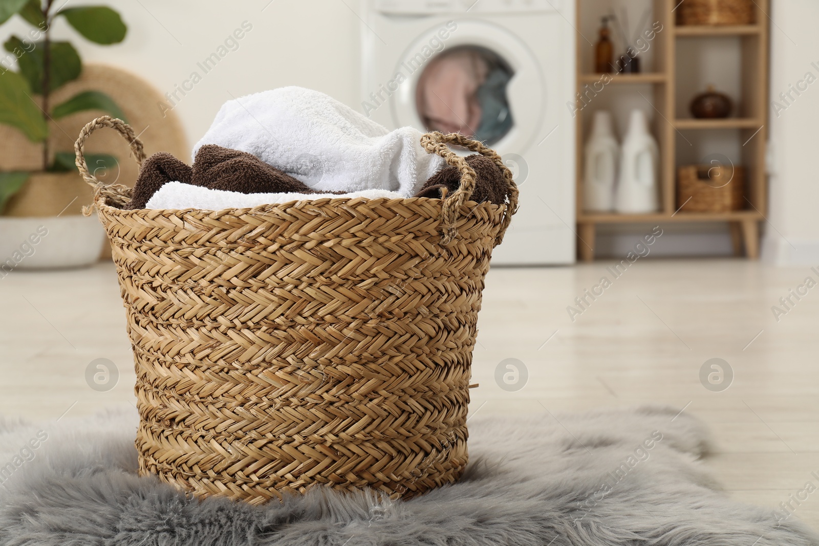 Photo of Wicker basket full of laundry in bathroom