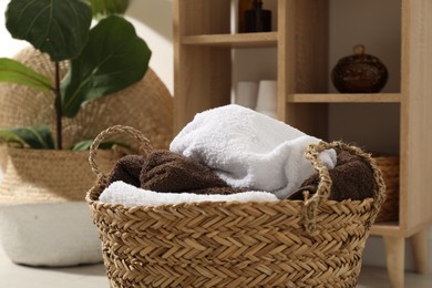 Photo of Wicker basket full of laundry in bathroom, closeup