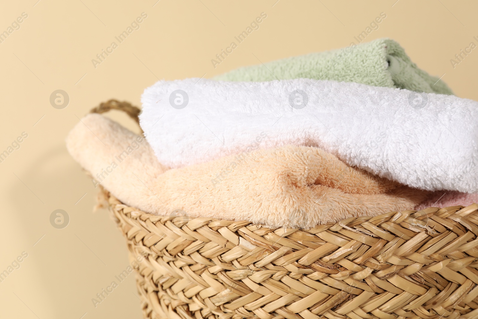 Photo of Wicker basket full of laundry against beige background, closeup