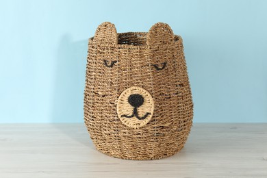 Photo of One wicker laundry basket on wooden table against light blue background