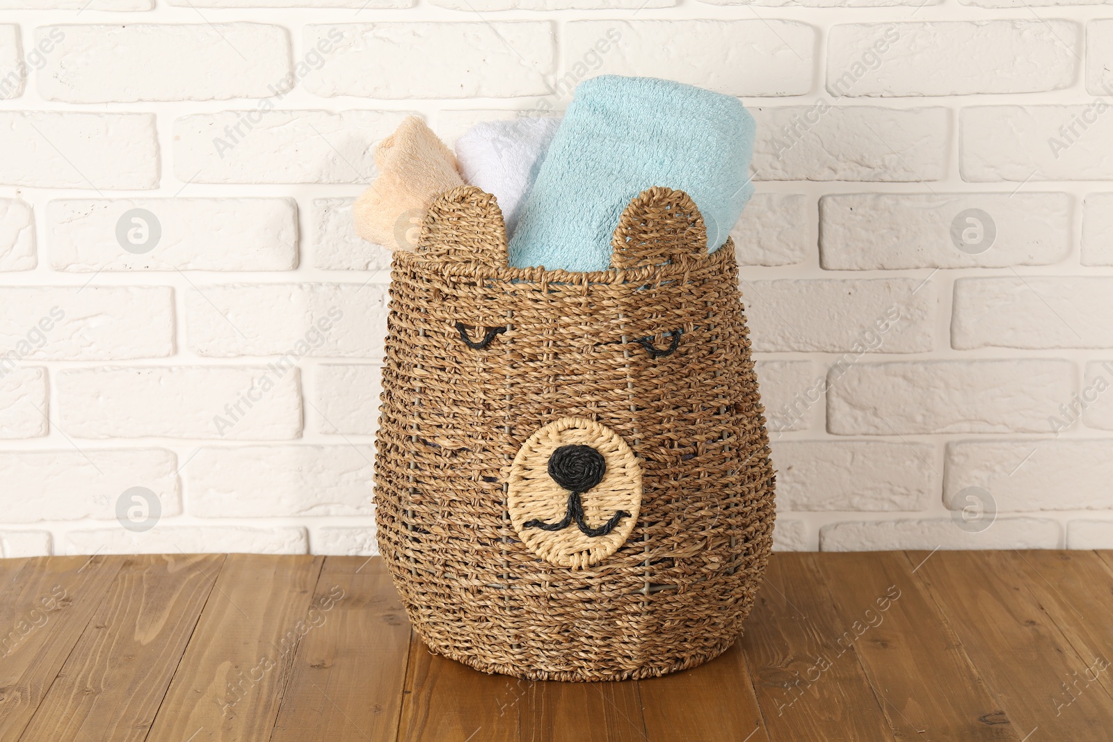 Photo of Wicker basket full of laundry on wooden table