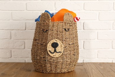 Photo of Wicker basket full of laundry on wooden table