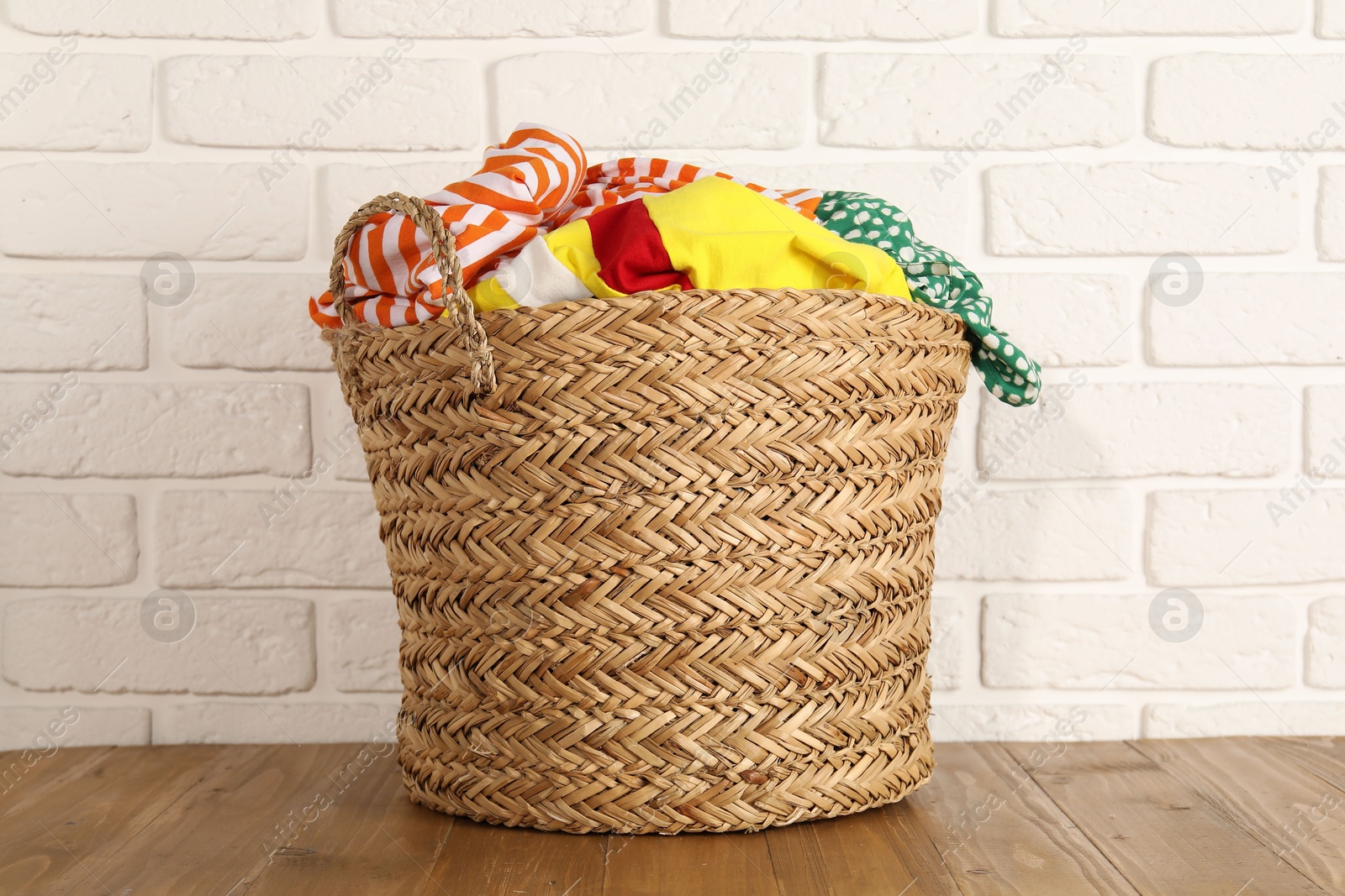 Photo of Wicker basket full of laundry on wooden table