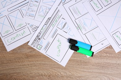 Photo of Developing UI design. Sketches of website wireframes and felt pens on wooden table, top view